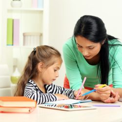Beautiful school girl doing homework with mother at home