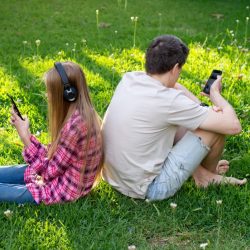 teen-boy-and-girl-sitting-on-grass-back-to-back-technology-153