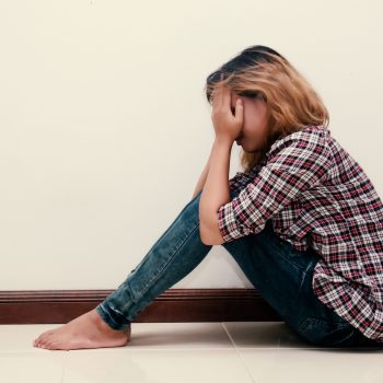 young hipster woman, sad, long-haired  sitting hugging legs.