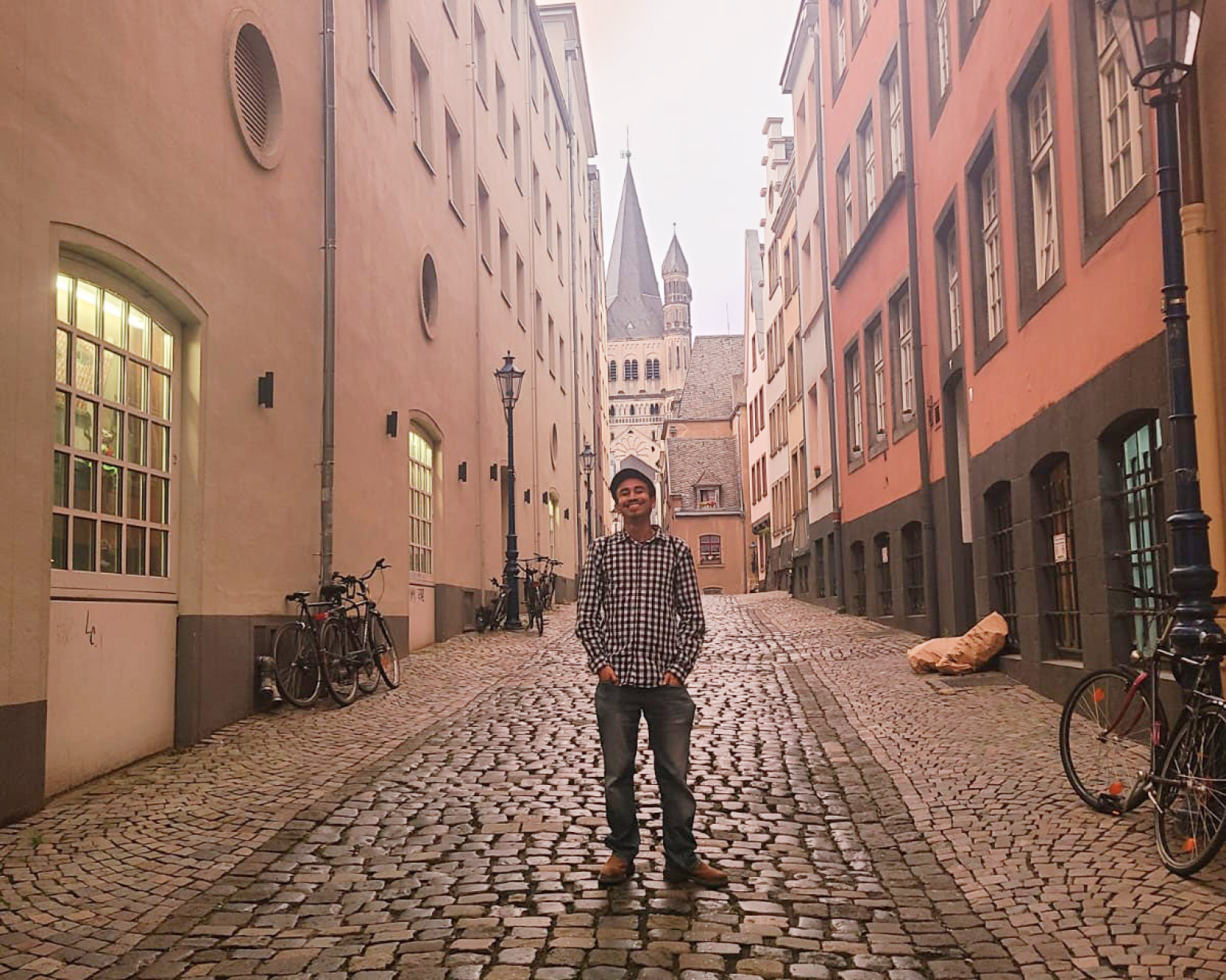 Photo of Alex Fuentes standing on a cobbled street in Cologne, Germany